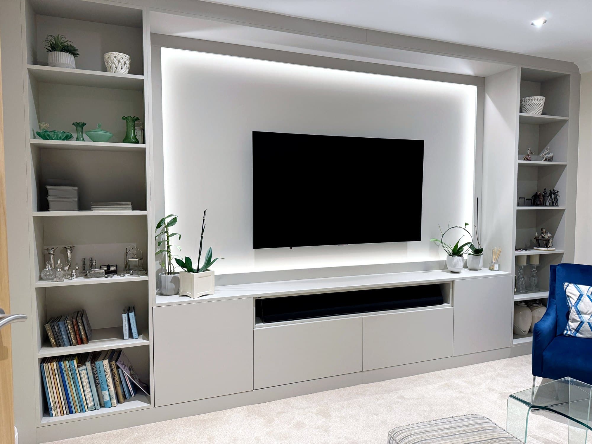 LED-backlit fitted media wall with display shelving